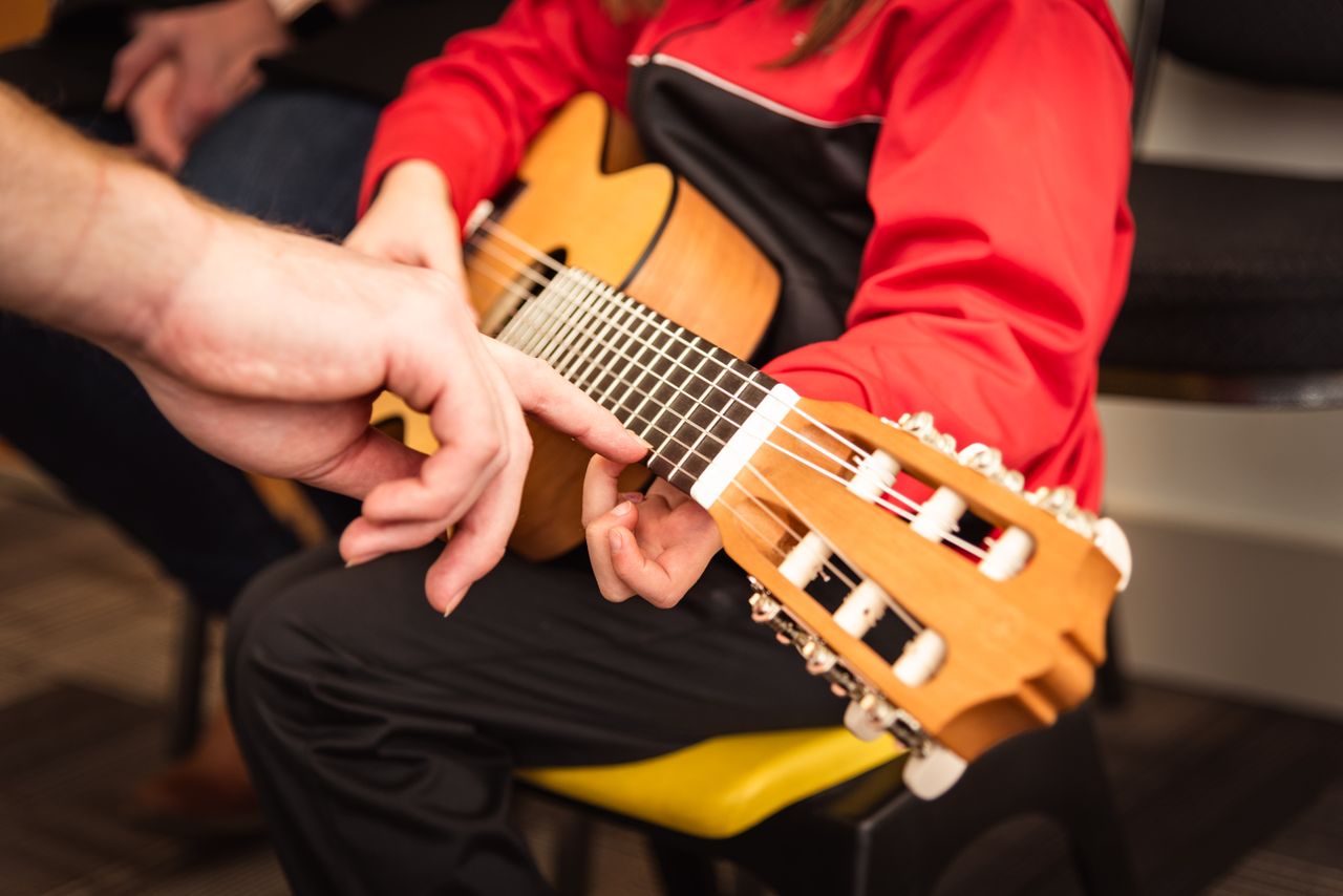 contact-img Child receiving guitar lesson with instructor's guidance in Victoria, BC. Focused on strings and technique.