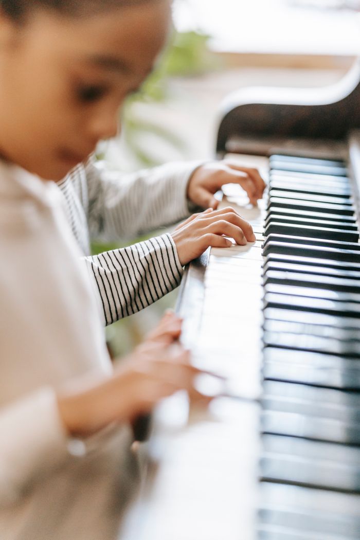 services-01 Side view of crop unrecognizable ethnic kids playing piano together in light room
