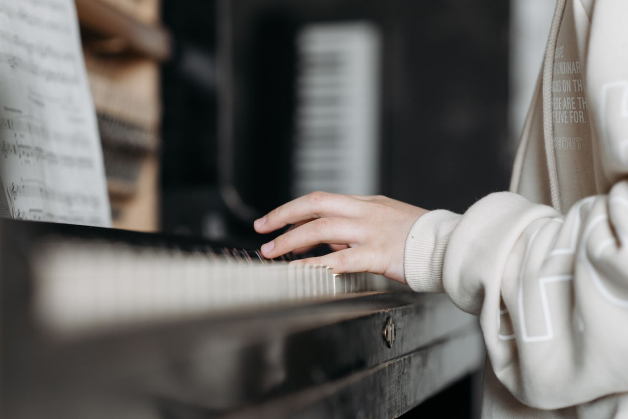 services-01 Hands playing piano with sheet music in cozy indoor setting. Perfect for music education visuals.