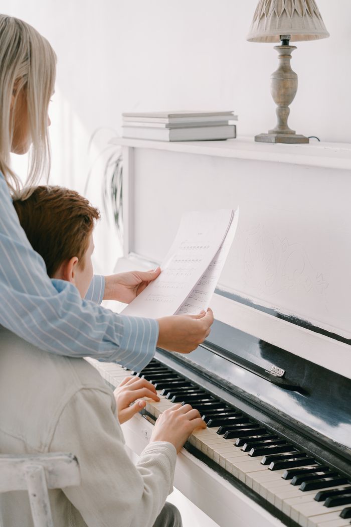 services-01 Focused piano lesson with a young student learning from a teacher in a bright setting.